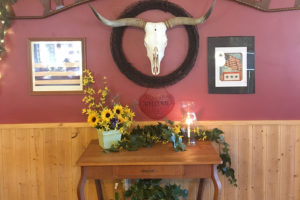 Wall with a framed bull scull above a welcome sign in Susie's Branding Iron
