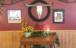 Wall with a framed bull scull above a welcome sign in Susie's Branding Iron